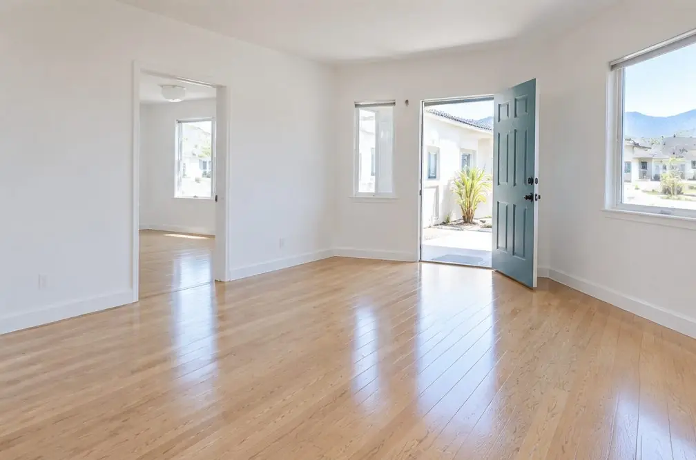 Illustration: an empty two-bedroom rental in Ontario, CA with a freshly refinished oak floor, bare walls and a front door open to a breezeway