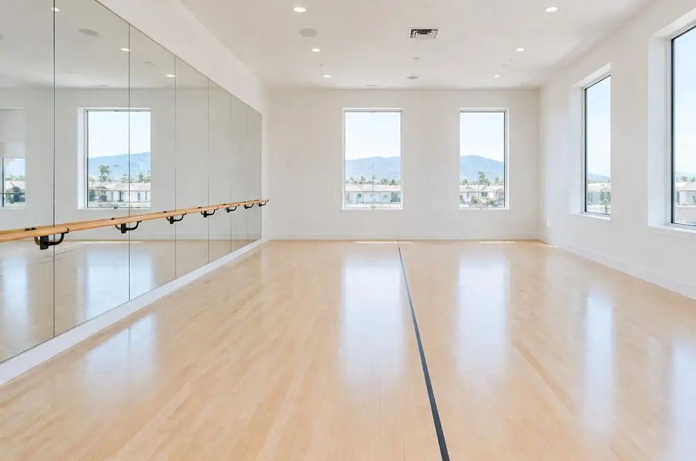 Illustration: a bright private dance studio in Ontario, CA with a pale maple floor, a mirrored wall, a ballet barre and a thin painted line near the center